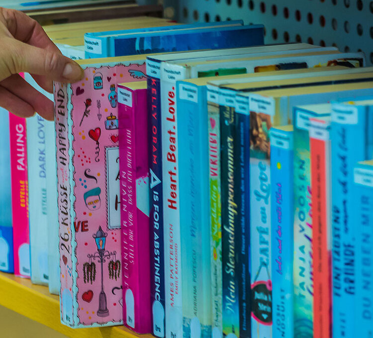 Kinderbuch im Regal Hand greift nach buntem Kinderbuch in Bücherregal.